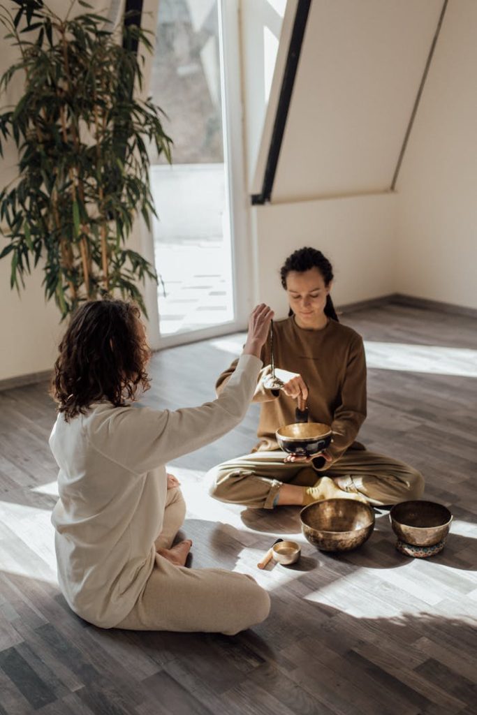 women-sitting-on-floor-doing-meditation-and-relaxation-with-tibetan-singing-bowls-and-tingsha-bells-6997995